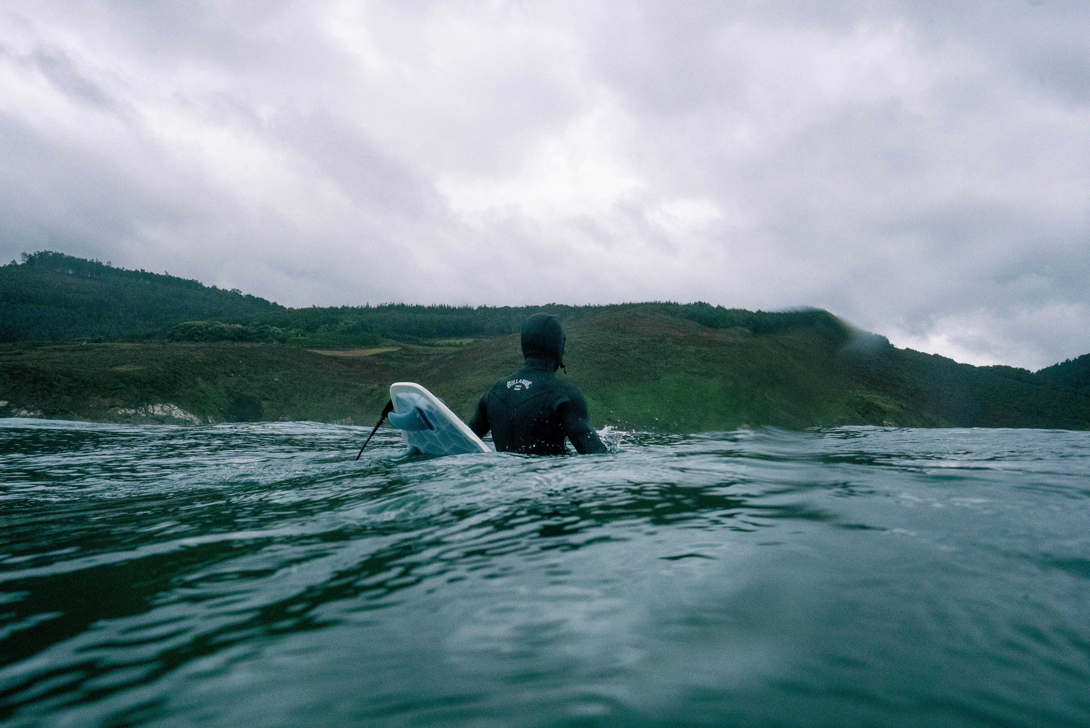 Surfer in a wetsuit waitting on the line up with a 3D printed surfboard