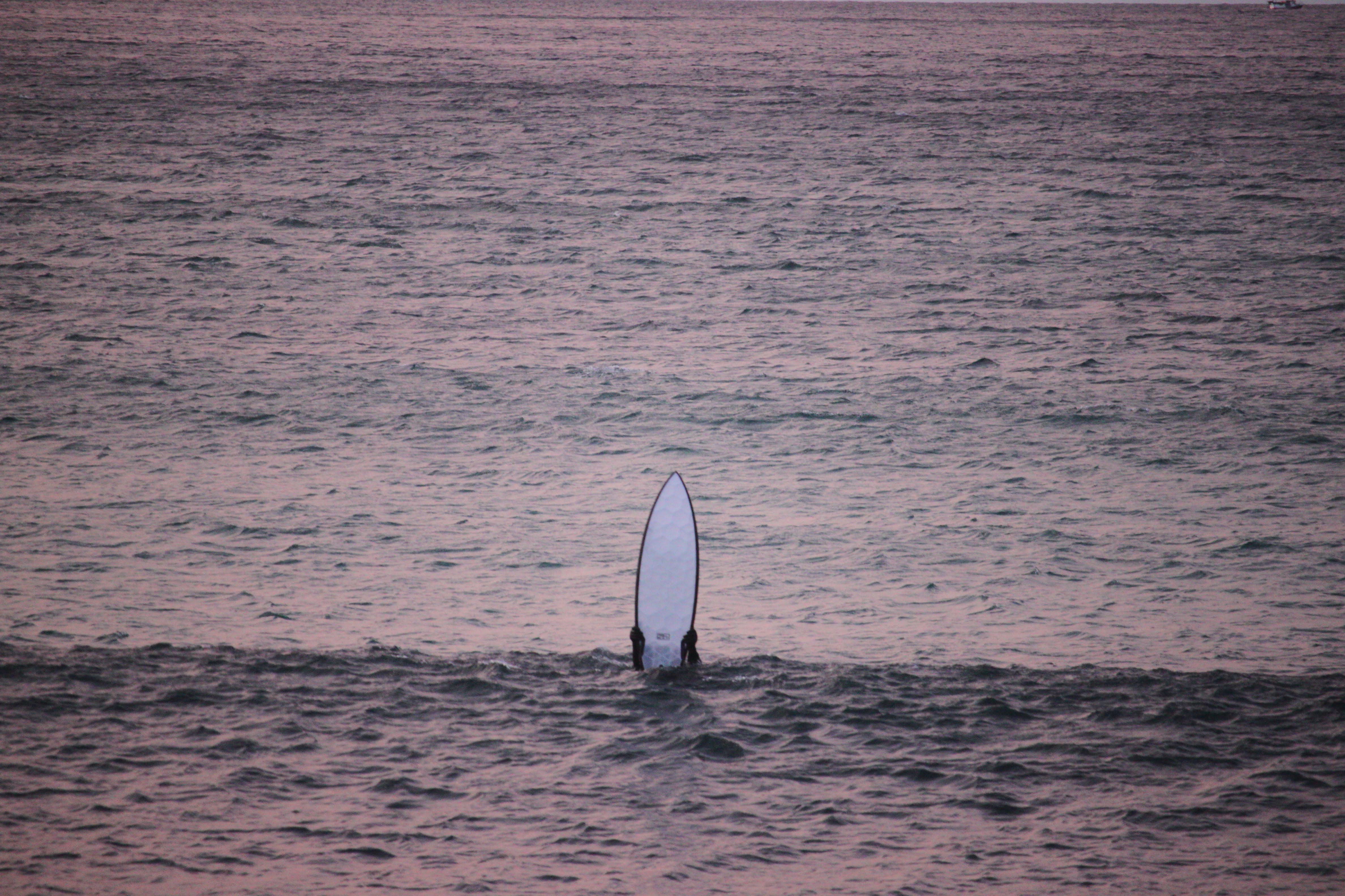 Surfer in the line up holding his transparent surfboard in the air