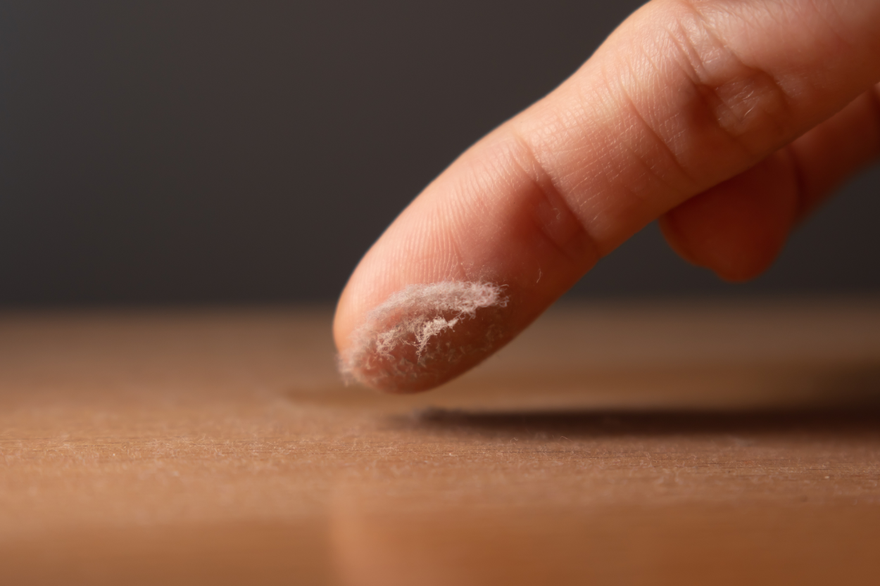 Finger wiping dust off a wooden surface