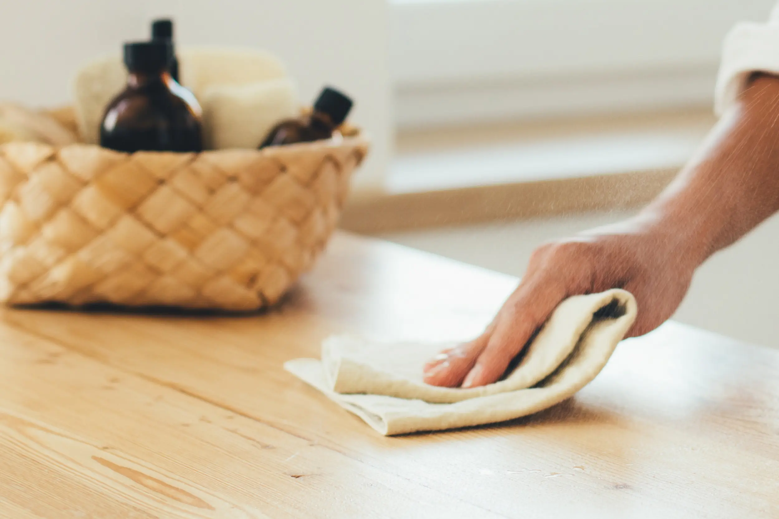 A photograph of someone wiping a countertop with a microfiber cloth