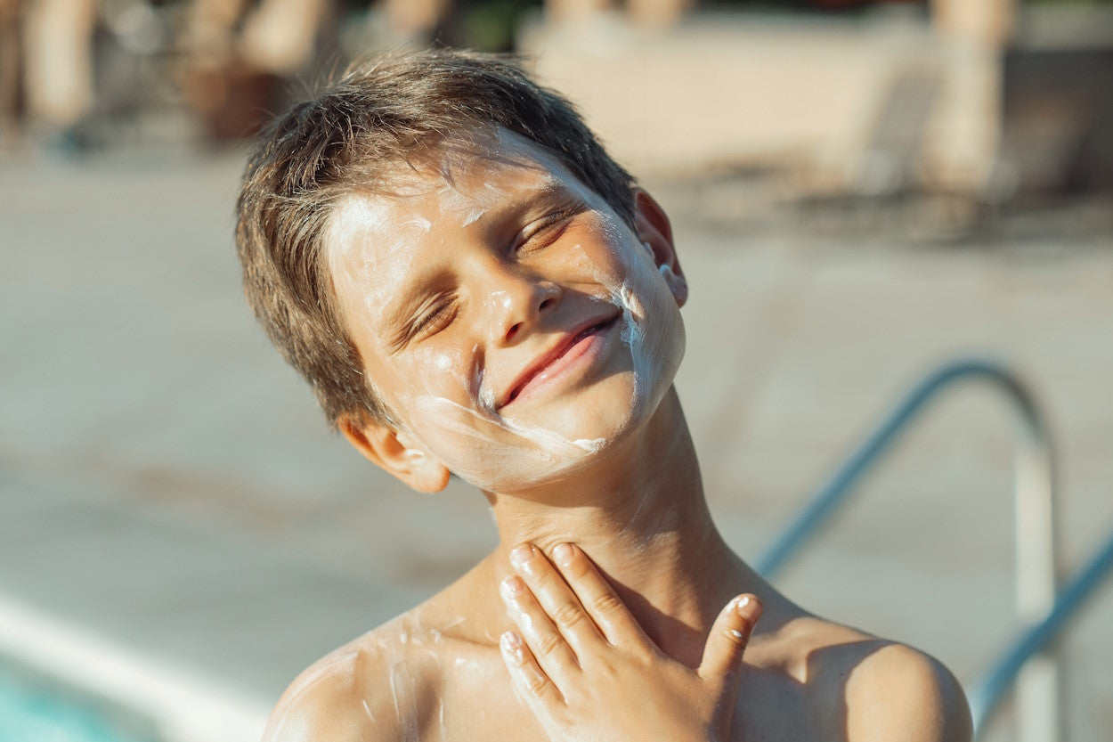 Boy applying sunscreen lotion