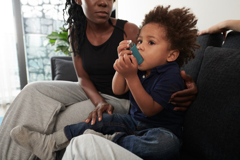 Mother watching as toddler uses inhaler