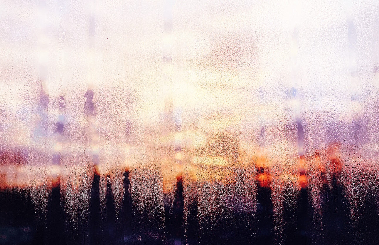 Condensation on a window with a city skyline blurred behind it