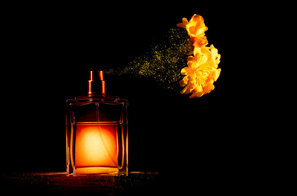 Dramatic shot of a perfume bottle spraying out flowers