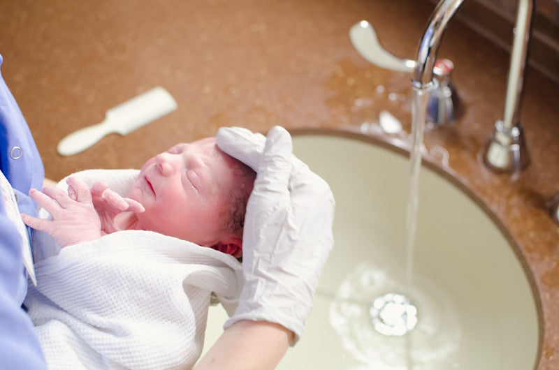 Newborn baby being washed by nurse