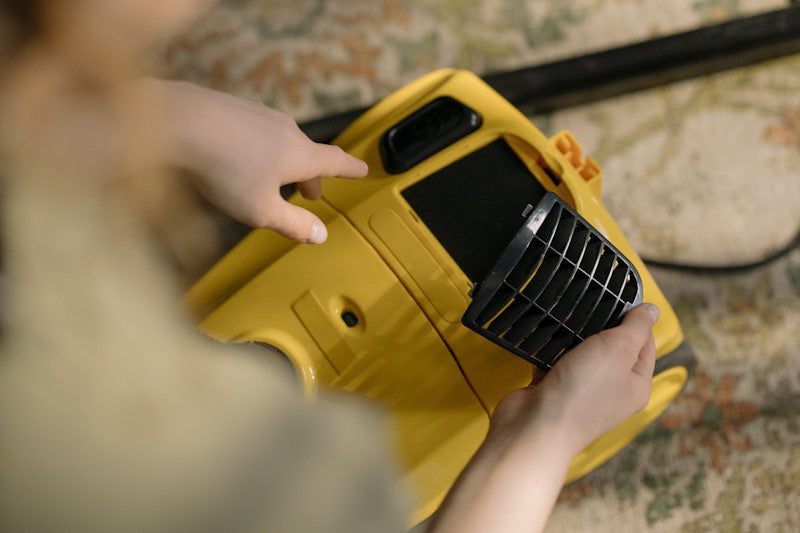 Woman removing vacuum cleaner filter