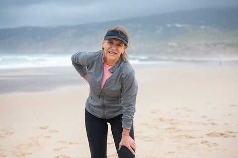 A woman looking uncomfortable in workout clothes on the beach