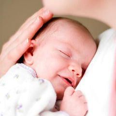 newborn baby smiling on mother's chest