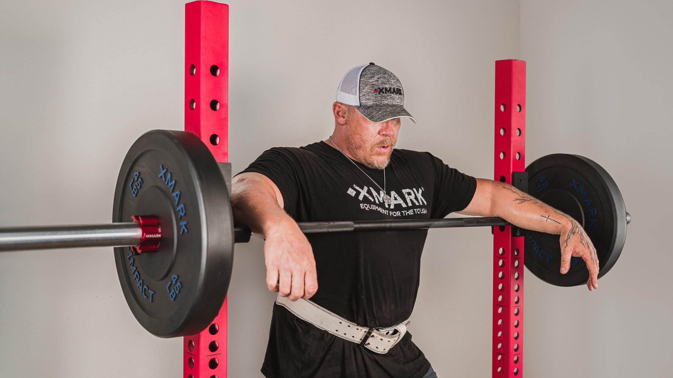 Man leaning on racked barbell