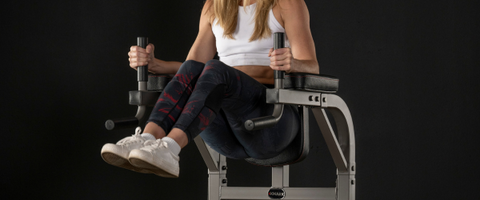 Woman performing leg raises on dip station