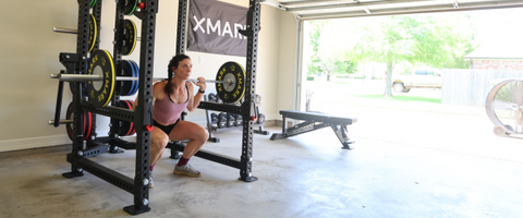 Woman back squatting in power rack