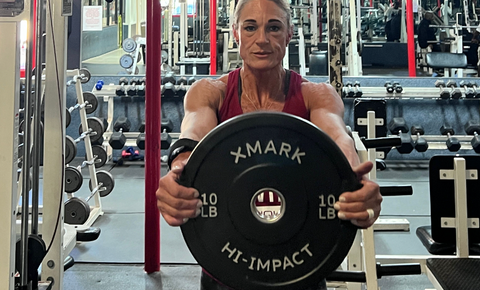 Female athlete holding XMARK iron plate directly in front of her