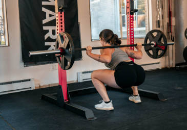 Woman back squatting with barbell