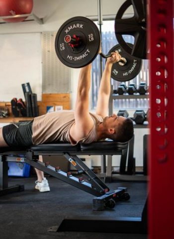 Man benching with a barbell on a weight bench