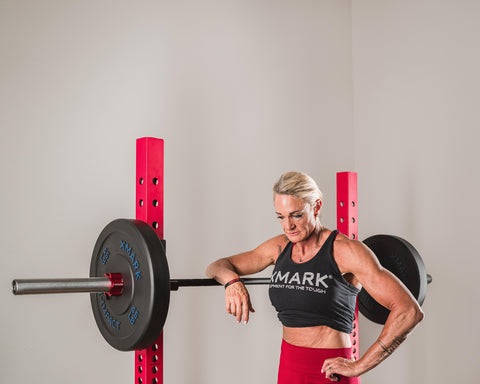 Female athlete resting her arm on racked barbell