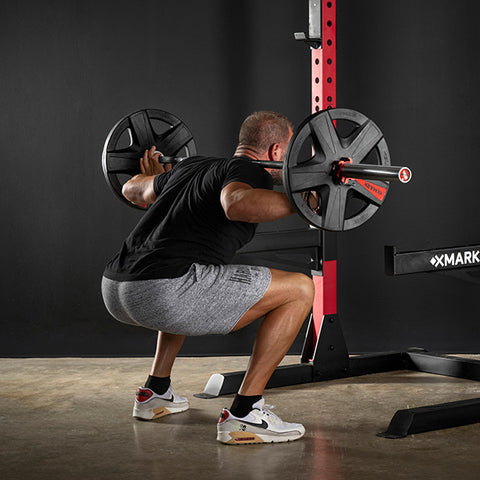 male doing squats with a squat rack