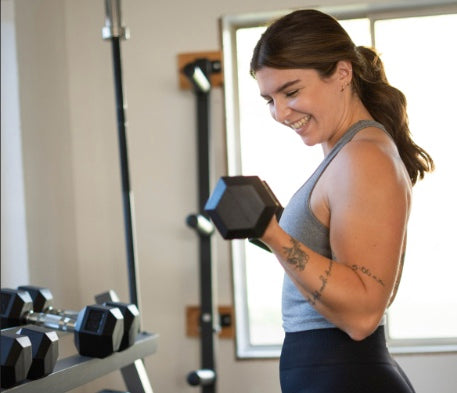 Woman curling dumbbells and smiling