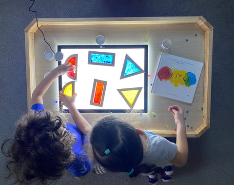children playing with transparent blocks on a light panel