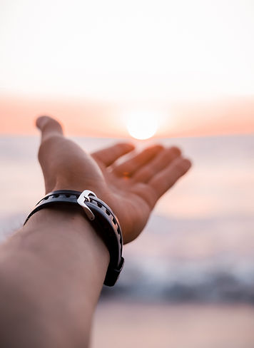 Man with rubber watch strap on watch reaching out to the sun