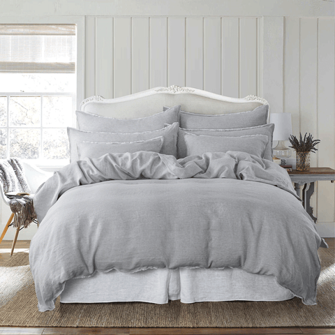 a bed with a white headboard and gray bedding