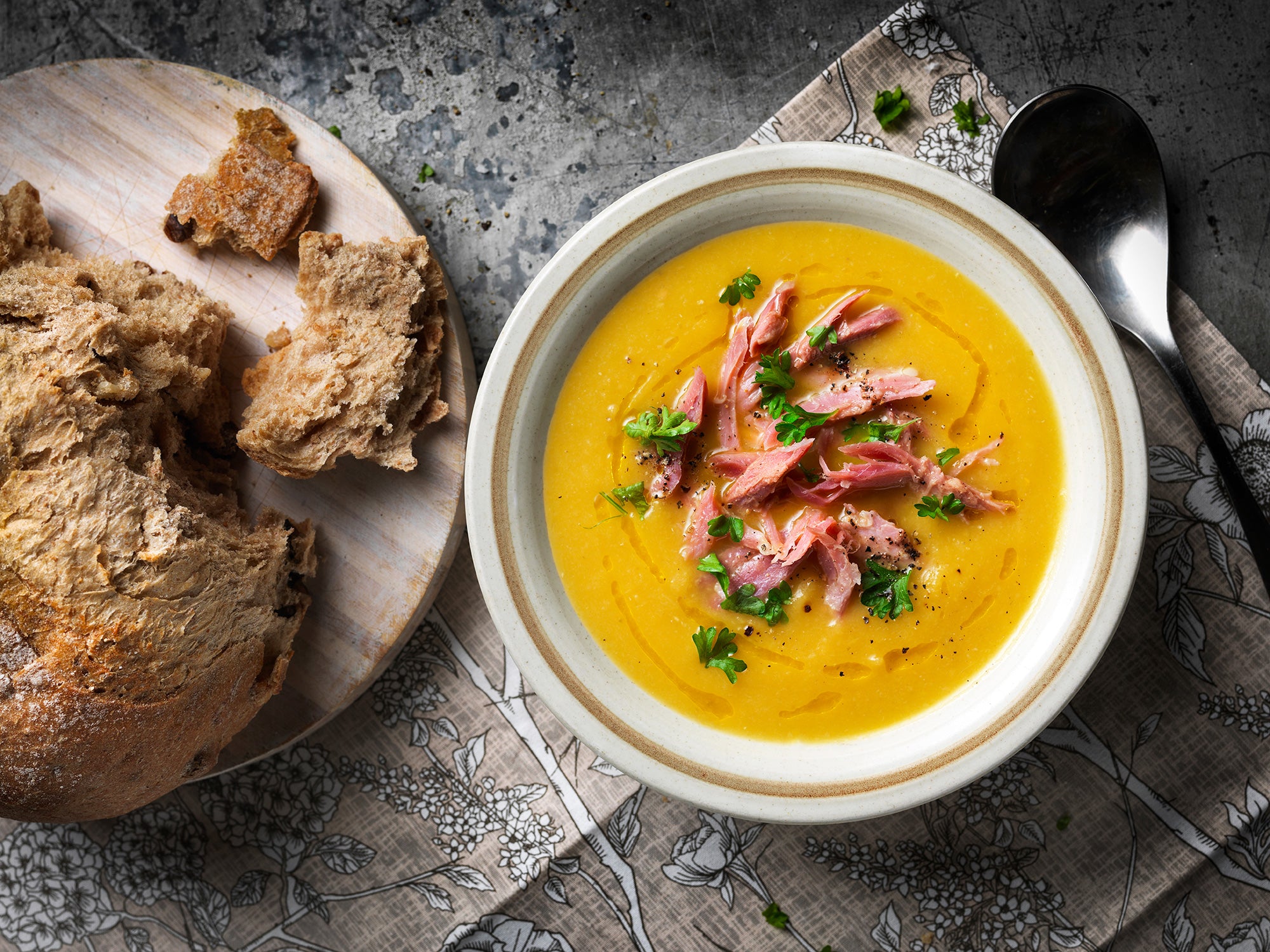 ham hock soup in bowl next to plate of bread