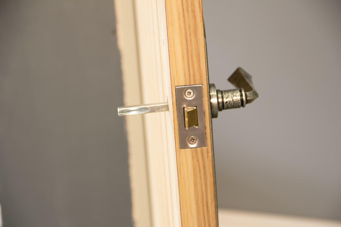 Mortice latch and Pewter door handle fitted to the edge of a wooden door.