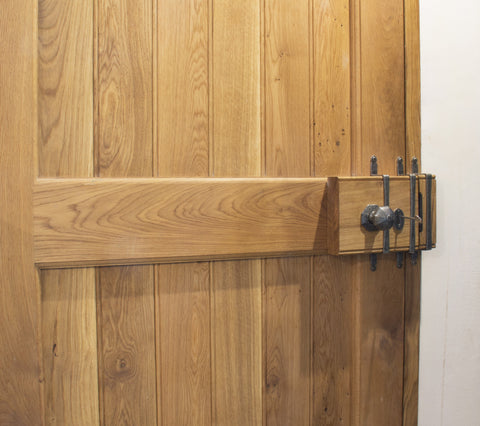 Wooden door with From The Anvil's Pewter Oak Box rim lock set with a key in.