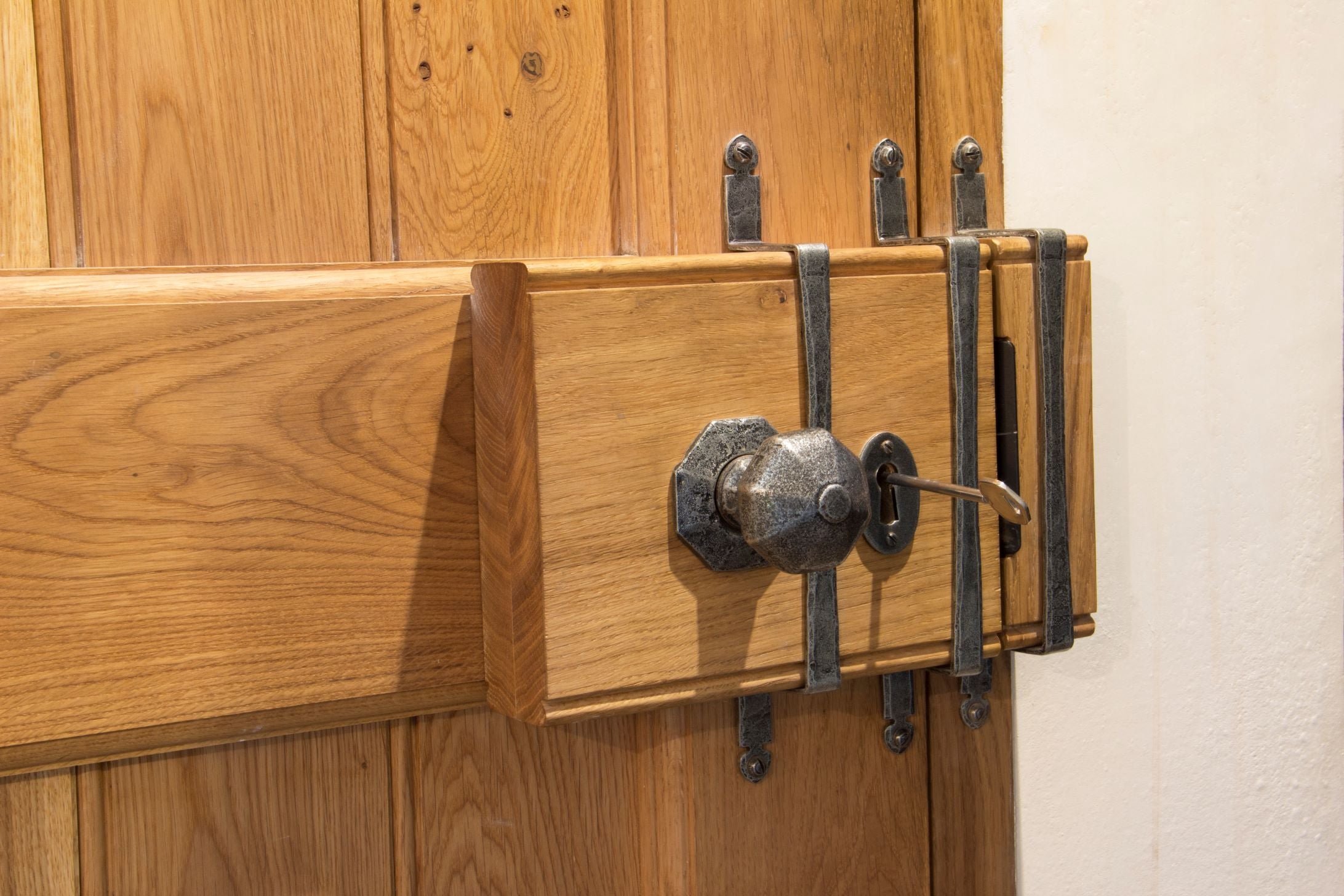Close up image of an oak box lock with a Pewter Octagonal knob and Pewter over-bars on a wooden door.