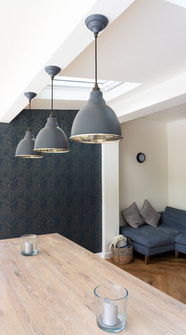 From The Anvil's Slate Grey Hammered Nickel Brindley ceiling pendant lights above a wooden kitchen table.