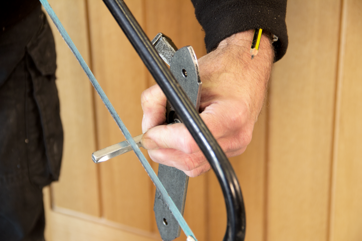 Person using a hacksaw to cut a spindle down to size.