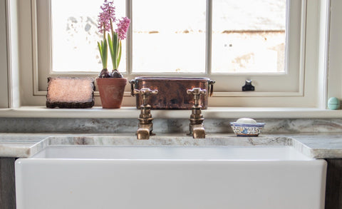 White ceramic sink with copper taps and a marble countertop, in front of a sash window with Aged Bronze From The Anvil sash lifts.