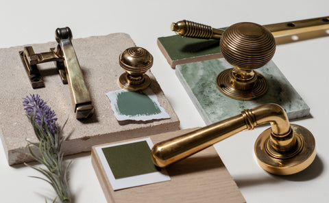 Moodboard of From The Anvil's Polished Brass door handles, window hardware and door knobs on green and neutral tiles with a lavender flower.