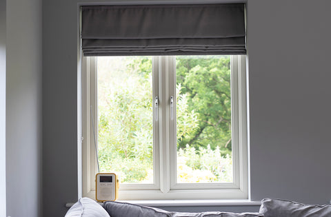 White uPVC window with basic white window handles and a grey blind, with a radio on the windowsill.