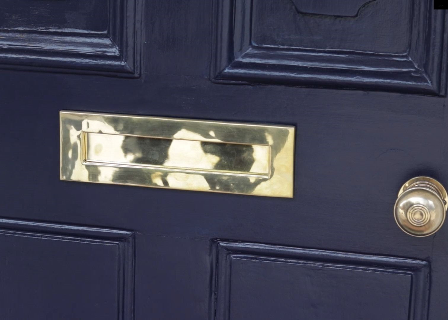 Dark blue painted door with a Polished Brass letterbox and matching door knob.