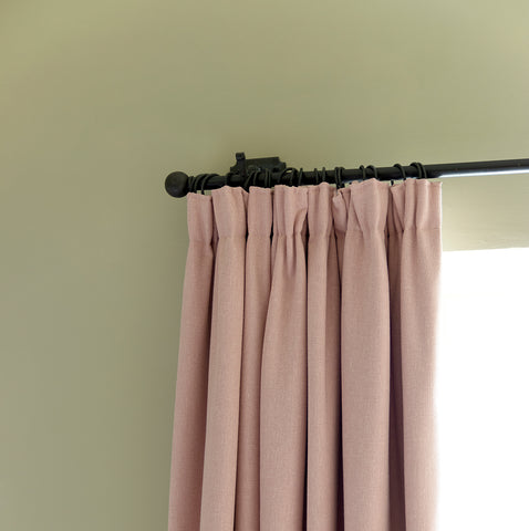 From The Anvil Beeswax curtain pole and curtain rings with pleated gathered pink curtains.
