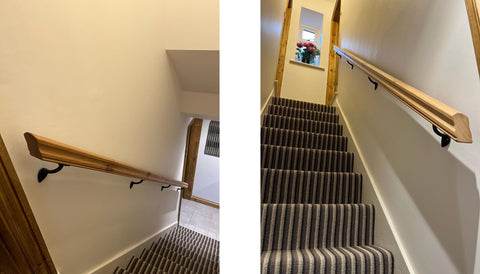 From The Anvil's Black handrail brackets supporting a wooden handrail in a narrow stairway with striped carpet stairs