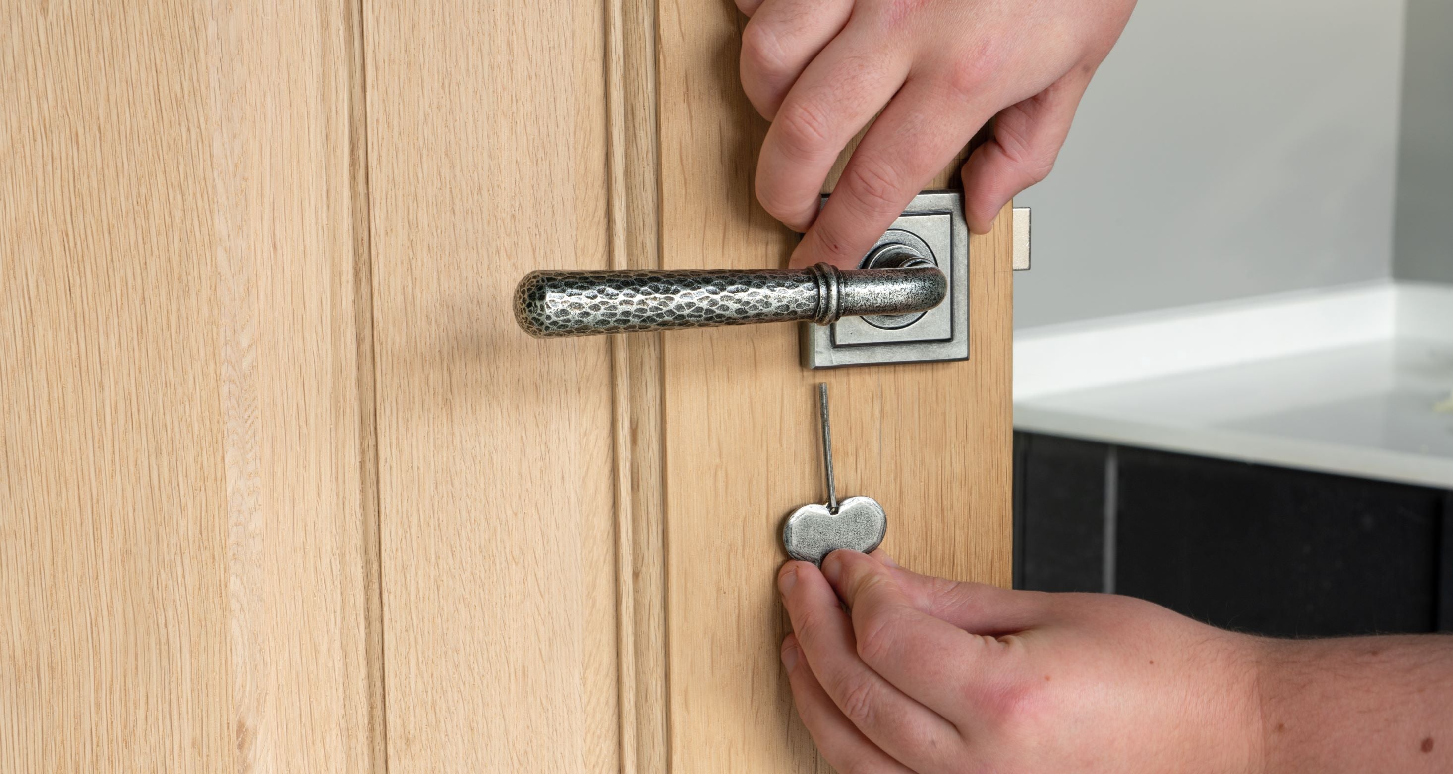 Person using an Allen key to tighten a Square lever on rose cover to a lever on rose door handle on a wooden door