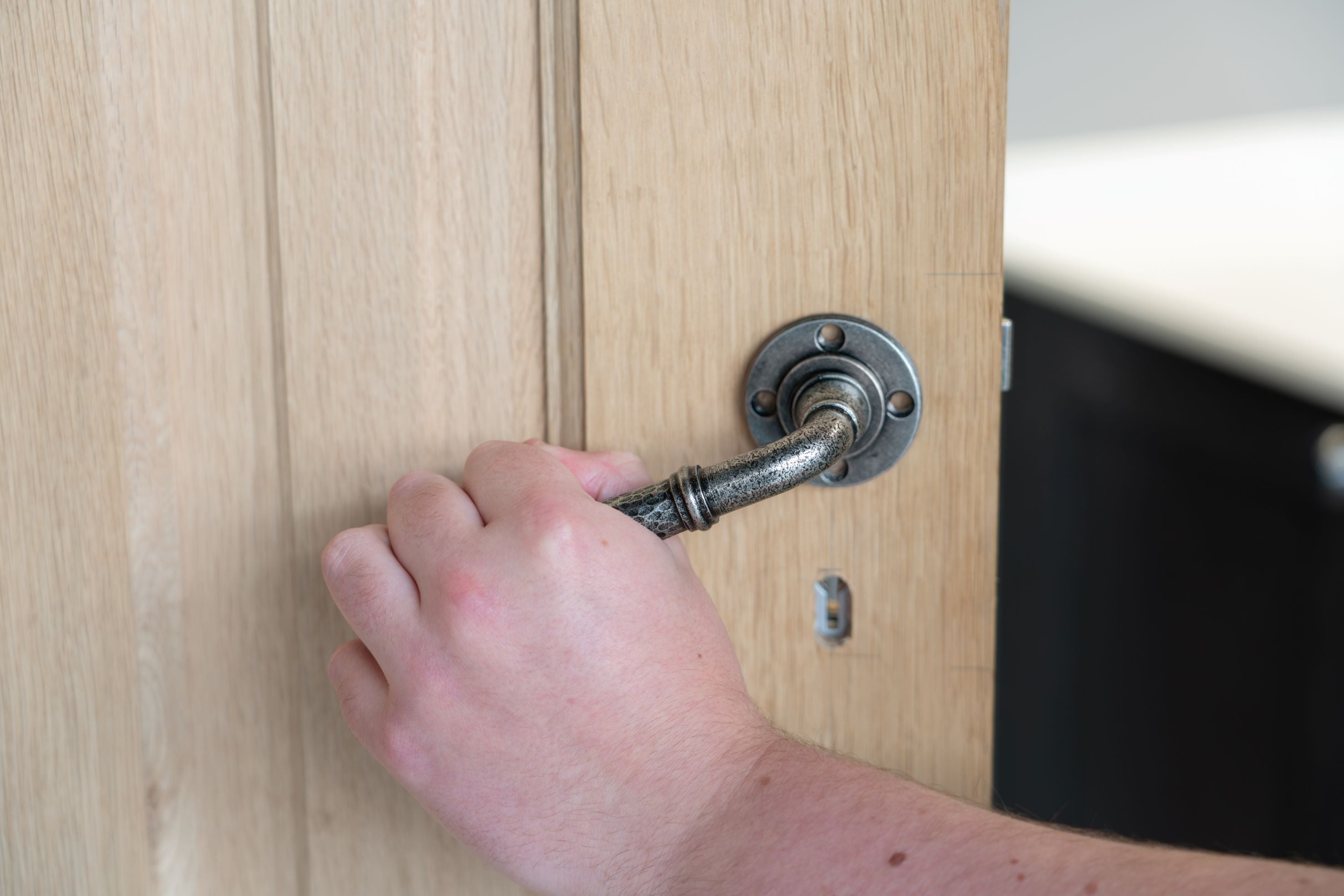 Person attaching a Pewter lever on rose door handle to a wooden door.