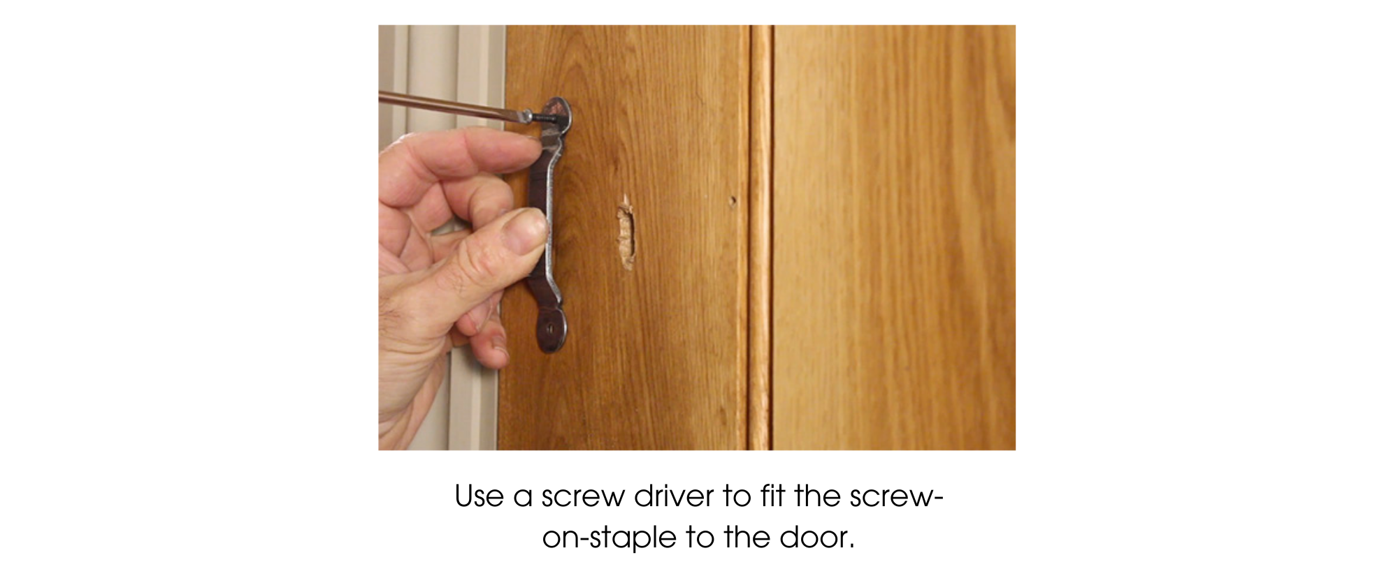 Person using a screw driver to fit a screw-on-staple part of a thumblatch to a wooden ledge & brace door.