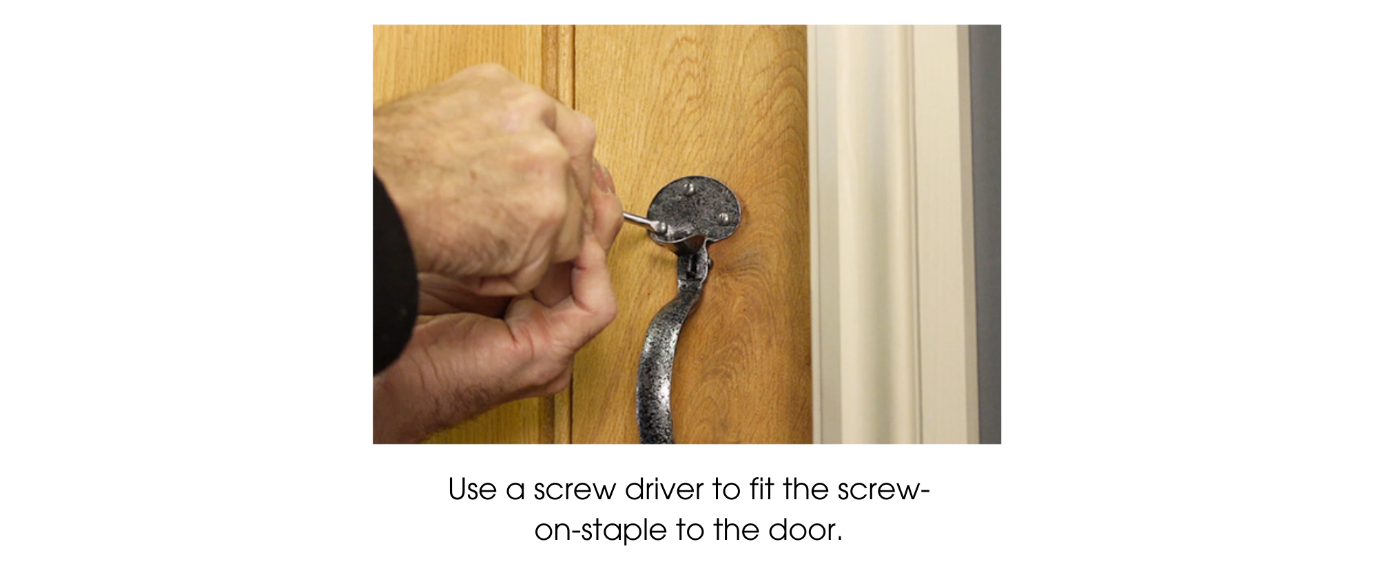 Person using a screw driver to fix a Pewter thumb latch handle to a wooden ledge and brace door.