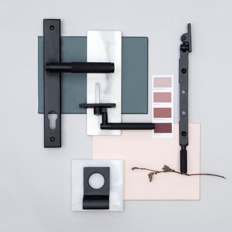 A moodboard of From The Anvil's Matt Black knurled door handle, window fastener, window stay & rim pull, with navy & pink paint samples and white marble tiles.