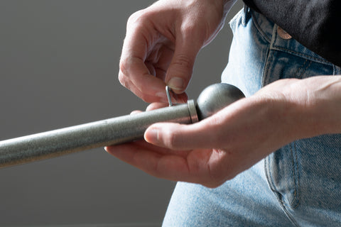 Person fitting a Pewter Ball finial to a Pewter curtain pole by tightening a grub screw with an Allen key.