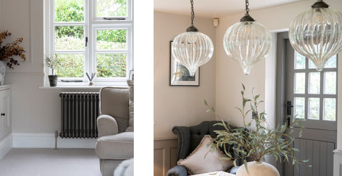 A neutral interior with painted stable doors, glass ceiling pendant lights, and a painted radiator, with From The Anvil's Aged Bronze Hinton window handles, window stays, and door handles.