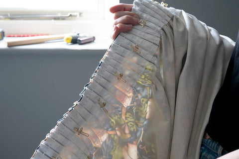 Person adding curtain hooks to a pleated curtain