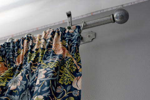 Pair of pleated curtains hung using From The Anvil's Pewter curtain hardware including their curtain pole, Ball finials, curtain rings, and mounting brackets.