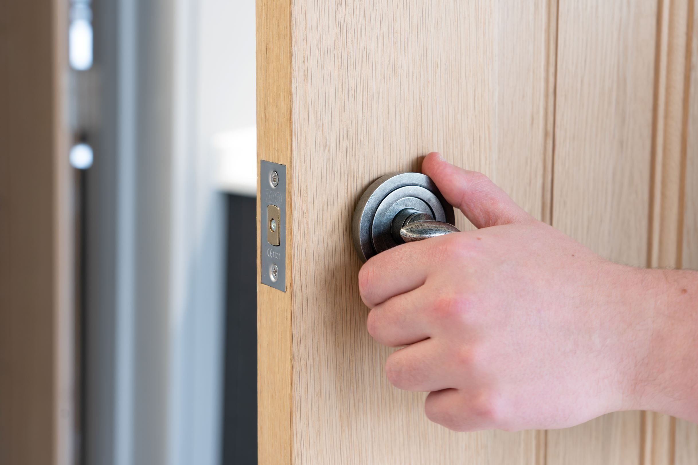 Person tightening a Pewter rose onto a thumbturn on a wooden door.