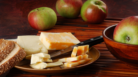 An image of apples and cheese on a dinner table in plates