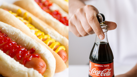 Image of a hotdog  with mustard and ketsup next to a bottle of coca cola