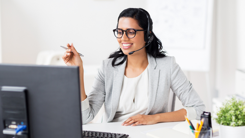 picture of business woman at a computer, smiling  wearing a headset