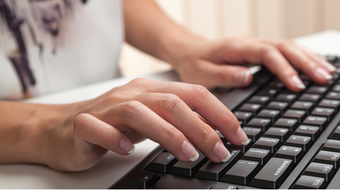 close up view of two hands typing on a computer keyboard
